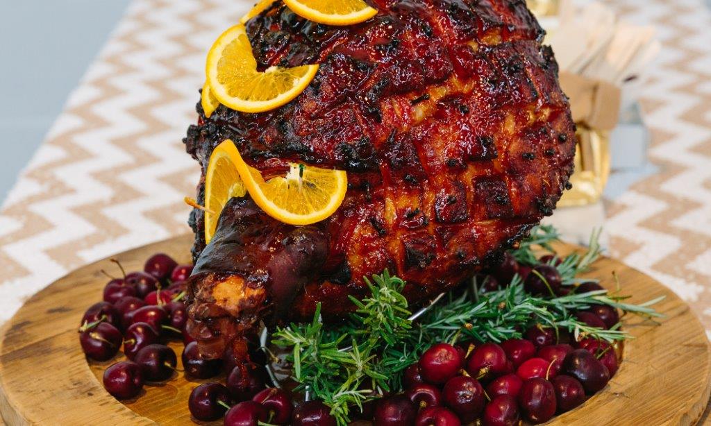 A Christmas ham with crackling skin, cherries, orange slices and rosemary. One of Chez Nous Corporate's incredible Christmas menu options.